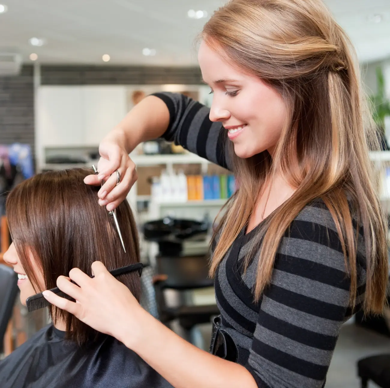 A woman is cutting another person 's hair