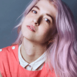 Person with pink hair and coral top.