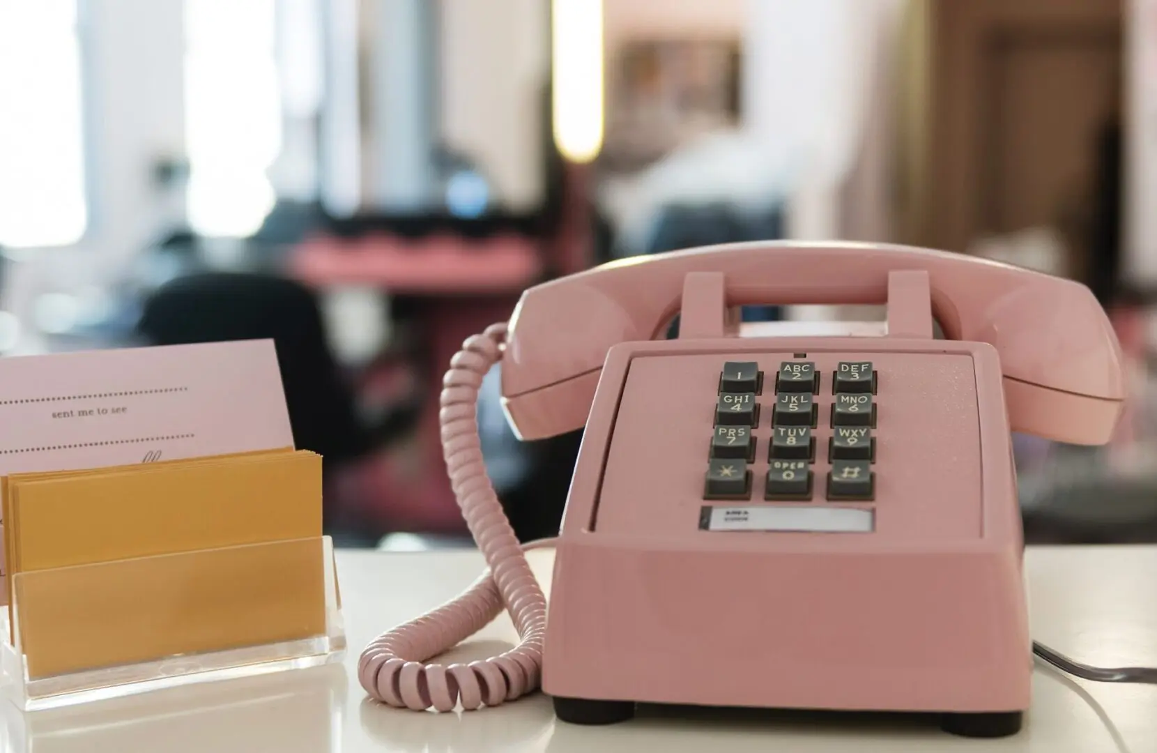 A pink telephone sitting on top of a desk.