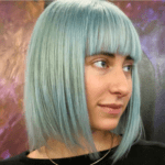 Woman with blue bob haircut, colorful background.