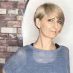 Woman with short blonde hair, smiling softly.