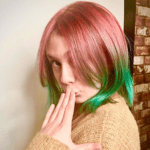 Person with pink and green hair posing.