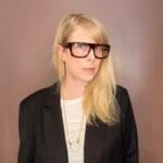 Person wearing glasses and black blazer.
