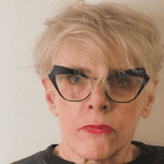 Person with glasses and short blonde hair.