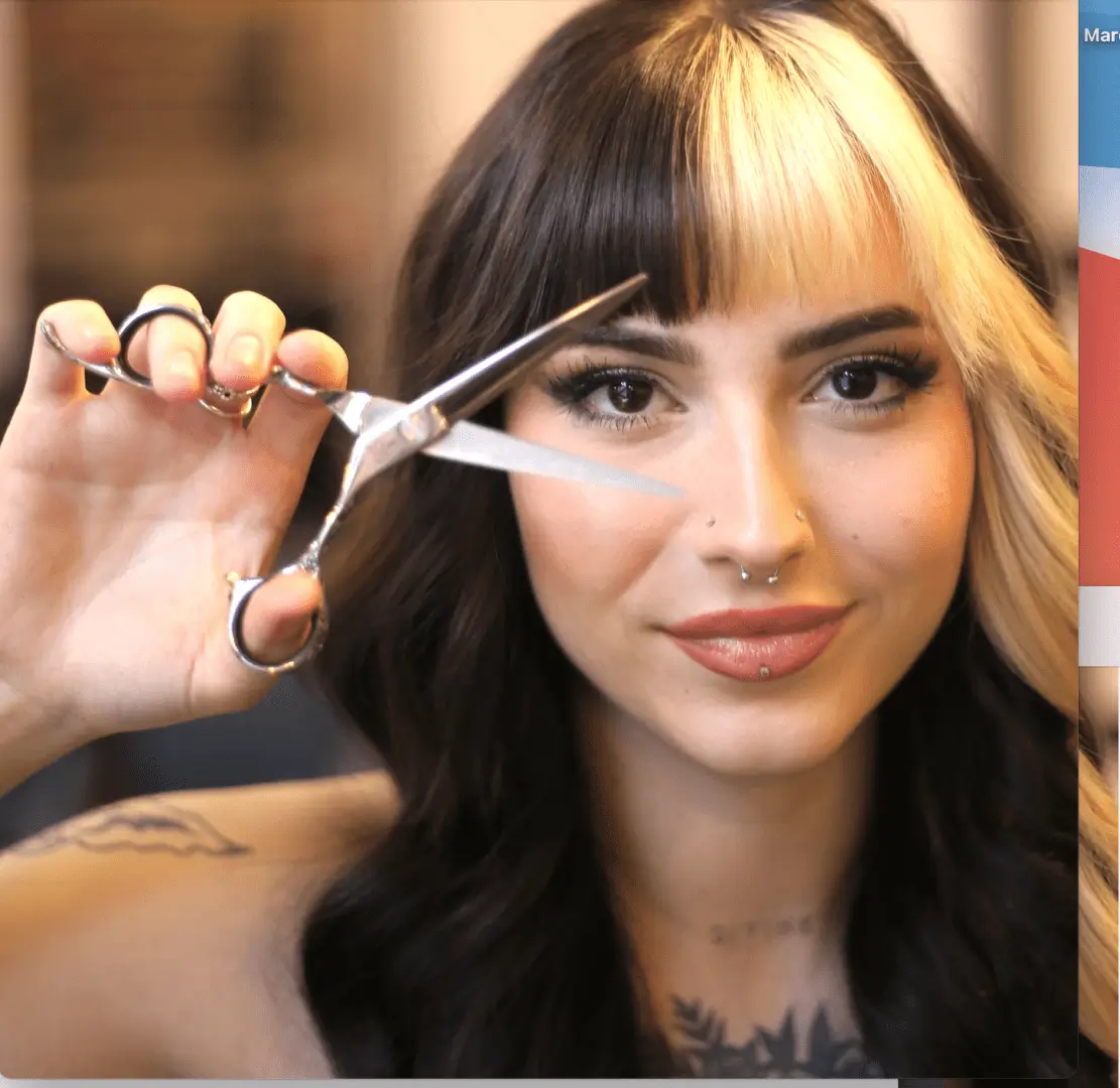 A woman holding scissors in her hand and looking at the camera.